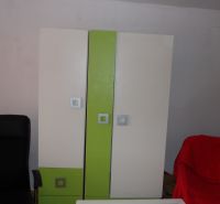 A wardrobe with colored doors and a black chair in a 2-room apartment.