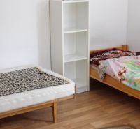 Two beds, a shelf, and a floor with a wooden decor in a 2-room apartment.