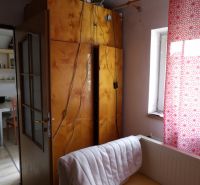 A room in a 2-room apartment with open doors, a cabinet, and a curtain with a red pattern.