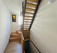 A staircase with a wooden decor in a family house with a bright interior and a painting on the wall.