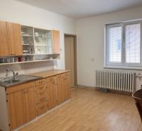 A kitchen with a wooden cabinet and a floor with a wood design in a family house.