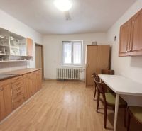 A kitchen in a family house with a wooden decor floor, wooden cabinets, and a dining table.