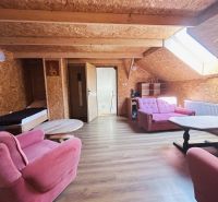 Attic room in a family house with pink furniture and a wooden decor floor.