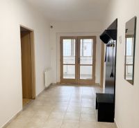 A hallway with a coat rack and tiles in a family house, the door leads to a glassed-in terrace.
