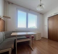 Dining area with seating and a wooden-patterned floor in a 2-room apartment.