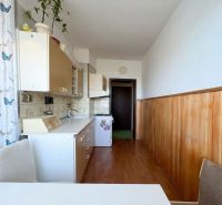 A kitchen in a 2-room apartment with a wooden floor decor and white cabinets.
