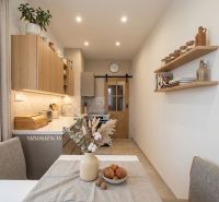 A kitchen in a 2-room apartment with wooden details and decorations on the shelves.