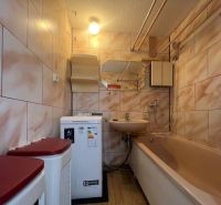 Bathroom in a 2-room apartment with a bathtub, sink, washing machine, and tiles.