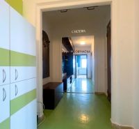 A hallway in a 2-room apartment with a green floor and furniture with white and green elements.