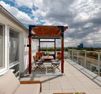 A terrace with a view of the city, with a pergola and outdoor seating in a 3-room apartment.
