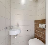 A bathroom with a sink, toilet, and a wall with wood decor in a 3-room apartment.