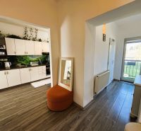 Interior with a kitchen unit, wooden decor flooring, and balcony doors in a 2-room apartment.