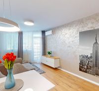 Living room with wood-patterned flooring, gray sofa, and a large picture of a skyscraper.