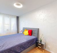 A bright bedroom with a bed, a nightstand, and colorful pillows in a 2-room apartment.