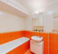 Bathroom in a 2-room apartment with orange and white tiles, a bathtub, and a sink.