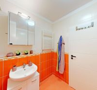 Bathroom in a two-room apartment with light-colored sanitary ware and orange tiles.