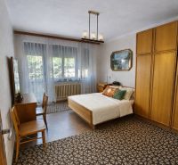 A bedroom in a family house with carpet flooring, a bed, and wooden furniture.