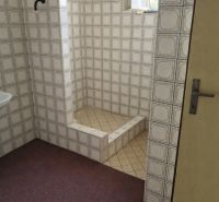 A bathroom in a family house with retro tiles and a shower corner.