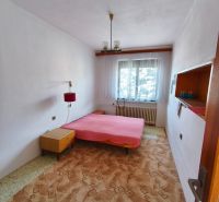 Bedroom in a family house with a bed, carpet, and a window with a white curtain.