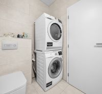 Washer-dryer in the bathroom of a 2-room apartment, light tiles and toilet.