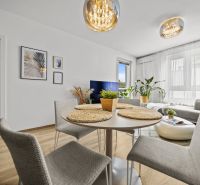Interior of a 2-room apartment with a dining area, wooden decor flooring, and an elegant chandelier.