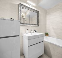 A bathroom with a mirror, sink, and bathtub in a 2-room apartment; clean and bright design.