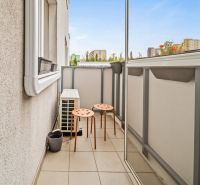 A balcony with two orange chairs in a 2-room apartment with a view of the city.