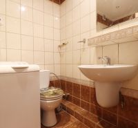 Bathroom in a 2-room apartment with a washing machine and toilet, tiles with a subtle pattern.