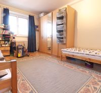 A bedroom with a large bed, wardrobe, carpet, and wood-patterned flooring in a 2-room apartment.