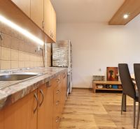 A kitchen in a 2-room apartment with wooden floor decor and wooden cabinets.