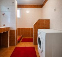 Bathroom in a family house with a shower and a washing machine, tiles in shades of brown.