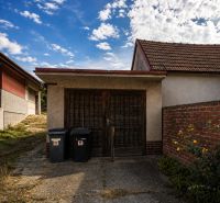 A family house with a garage in Šalgočka, with two trash bins and a brick wall.
