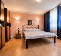Bedroom with a metal bed, wooden decor flooring, furniture, and curtains in a family house.