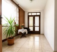Interior of a family house with ceramics, a plant, a table, and an upholstered armchair.