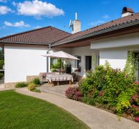 A family house in Šalgočka with a terrace, garden, and a sunshade on a grassy plot.