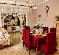 Dining room in a family house with red placemats, a kitchen, and decorations with an antique wall clock.