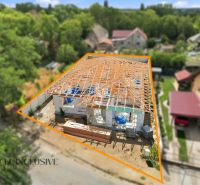 A family house in Marcelová under construction, surrounding houses and greenery in the background.