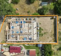 A family house construction in Marcelová from above, surrounded by an orange frame, encircled by greenery.