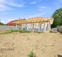 An unfinished family house in Marcelová with fencing, standing on an empty plot with grass.