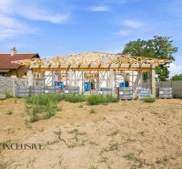 Construction of a family house in Marcelová with a roof under construction and fencing.