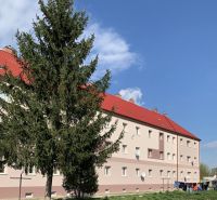 A building with red roofs and a tree in front of it, on Železničná Street in Šahy.