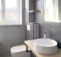 A bathroom in a studio apartment with a sink and a floor with a wood design.