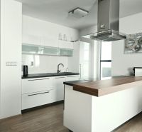 A kitchen in a 4-room apartment with a kitchen unit and an island, flooring with a wooden decor.