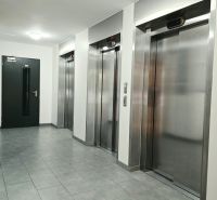 A hallway with four metal elevators and gray tiles in a 4-room apartment.