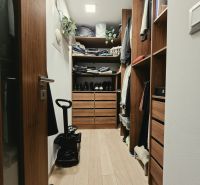 A wardrobe with cabinets and shelves in a 4-room apartment with a wood-decor floor.