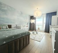 Bedroom in a 4-room apartment with wood-patterned flooring, a bed, and a baby crib.