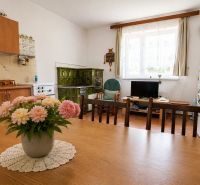 A kitchen in a family house with a tiled stove, a dining table, and floral decoration.