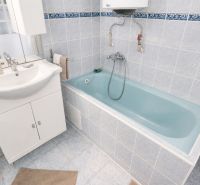 A bathroom with a white sink cabinet and a blue bathtub in a family house.