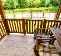 A wooden terrace with a view of the garden in a family house.