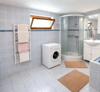A bathroom in a family house with a bathtub, shower, and washing machine.